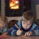 Brother and Sister Lying on the Floor in the Room Writing and Drawing Fireplace in the Background. - VideoHive Item for Sale