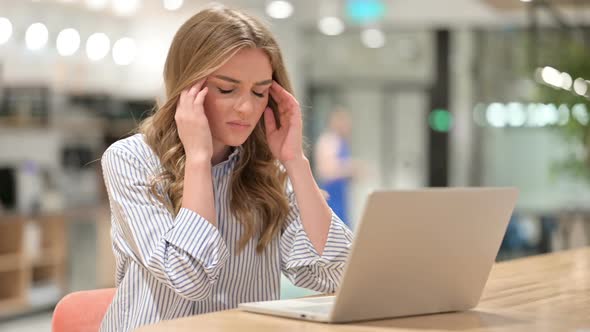 Stressed Businesswoman with Laptop Having Headache in Office