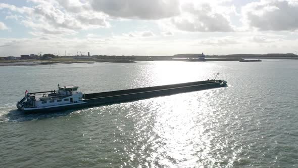 Beautiful aerial of long cargo ship sailing over sea with the coast in the background