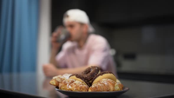 Closeup Delicious Sweet Doughnuts on Plate with Blurred Caucasian Gay Man Entering Kitchen Hugging