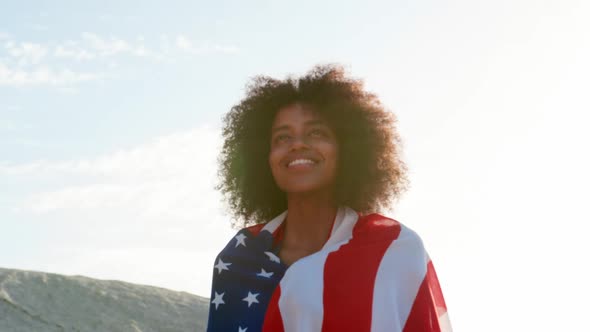 Woman wrapped with american flag and standing on beach 4k