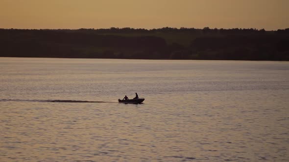 Motor boat floating in water on the forest background at dusk