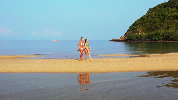 Women relaxing on idyllic lagoon beach lifestyle by shallow ocean with bright sandy background of Ko