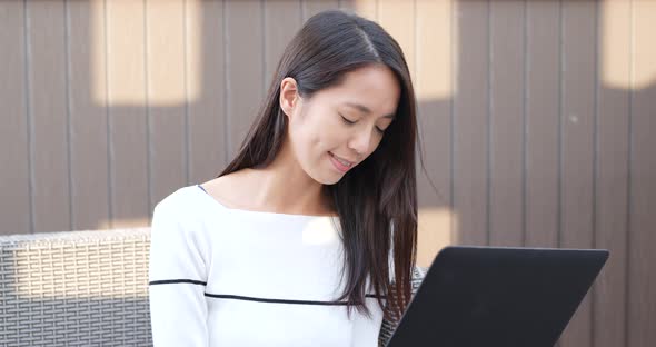 Woman working on laptop computer at outdoor coffee shop