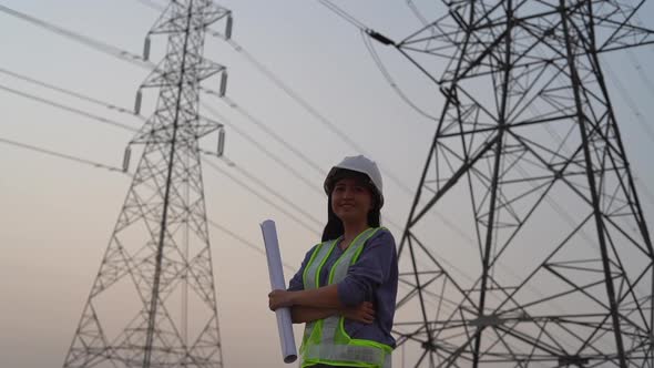 Female electrical engineer working near to High voltage tower.