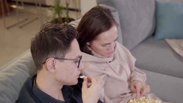 A Woman and Her Teenage Son are Watching TV and Eating Popcorn
