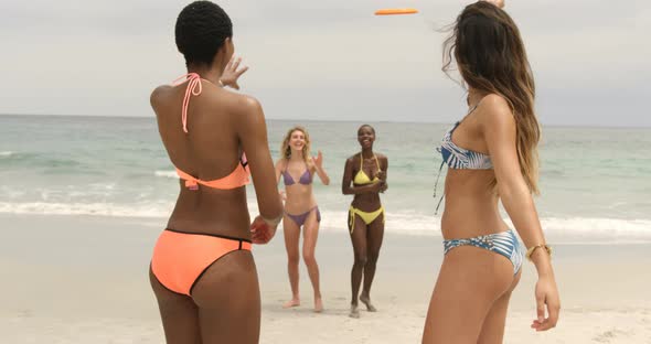 Group of mixed-race female friends playing flying disc on the beach 4k