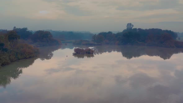 Landscape with lake view and a single road bordering it at misty autumn morning in Central Europe. A