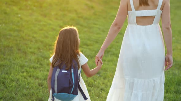 Schoolgirl with Blue Backpack Goes Home Holding Mother Hand