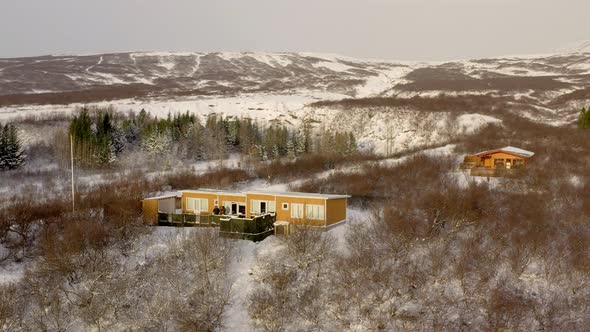 Aerial View Of Mountain Cabin During Wintertime With Forest Landscape.