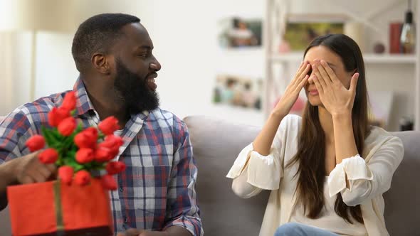 Black Man Presenting Tulips and Gift Box to His Girlfriend, Holiday Celebration
