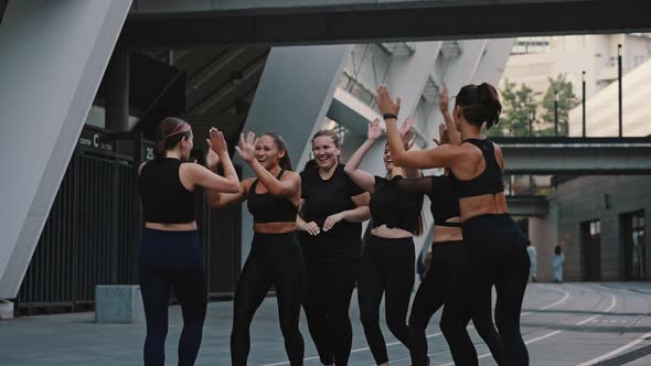 Group of Girls in Black Jerseys Give Each Other a High Five Outdoors