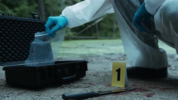 Criminalists Putting Proofs Into Protective Case at Crime Scene Closeup Taking Evidence From