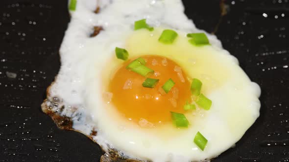 Sprinkling green scallion on sunny side up eggs
