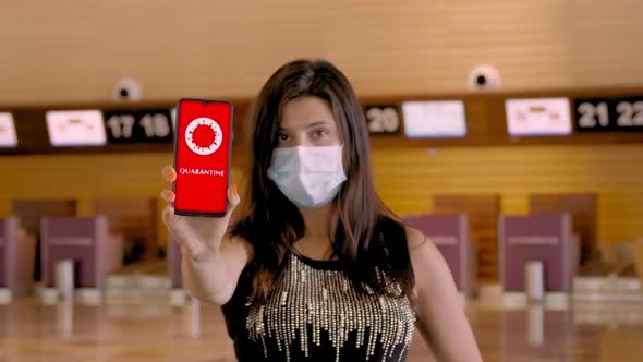 Woman, in Protective Mask, Holds Smartphone with COVID-19 Icon, Text - Quarantine, on Screen, in
