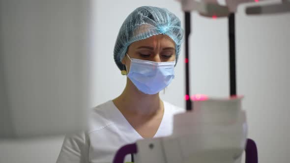 Portrait of Focused Beautiful Doctor in Face Mask Examining Xray with Cone Beam Scanner