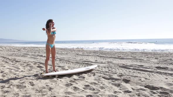 A young woman surfer stretching on the beach.