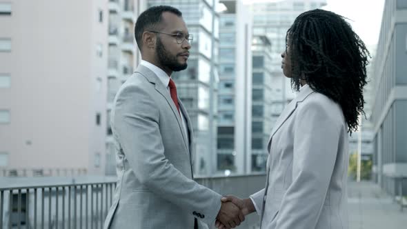 Smiling Man and Woman Shaking Hands on Street