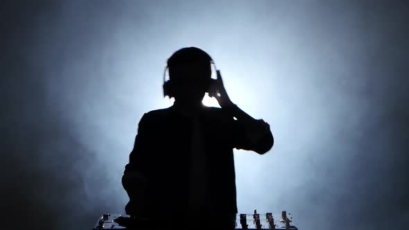 Silhouette Boy Dj in Headphones Playing on Vinyl. Smoky Background