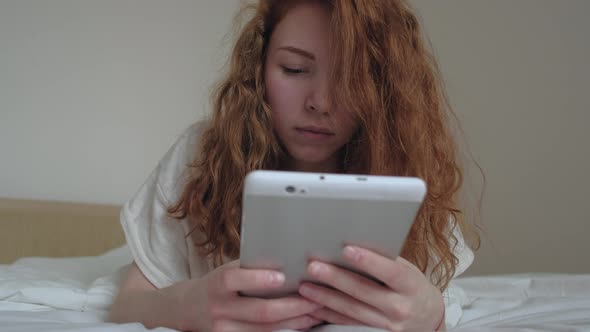 Good Looking Redhairs Girl with a Digital Tablet in Her Bedroom