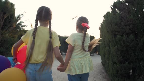 Little Pretty Girls Having Fun Outdoor in Park. Two Cute Girls Are Running on Green Grass with Air