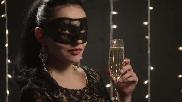 Sexy Woman in Venetian Mask Drinking Champagne