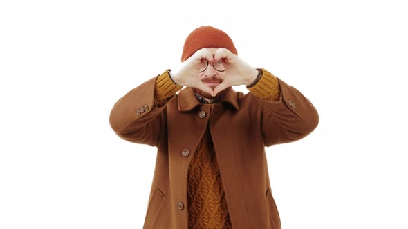 Young Caucasian Man Making a Heart Shape with Fingers Expressing Love and Positive Feeling Medium