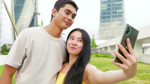 Young asiatic couple in love outdoors taking selfie smilling happy enjoying time together