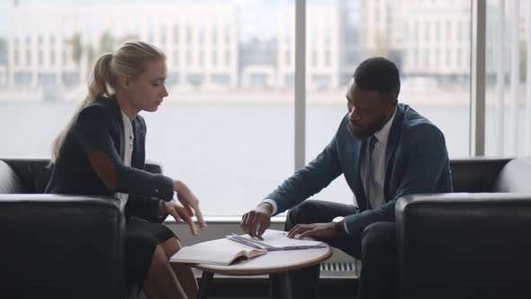 Two Business People Sitting at the Table in Office and Signing Contract.