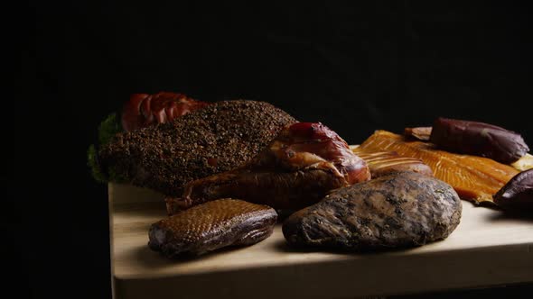 Rotating shot of a variety of delicious, premium smoked meats on a wooden cutting board