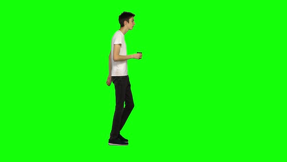 Tall Skinny Teen Guy Calmly Walking and Drinking Coffee on Green Screen Background. Chroma Key, Shot