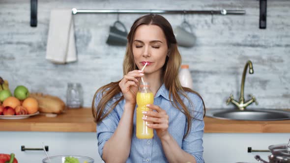Portrait of Smiling Young Blonde Woman Drinking Fresh Orange Juice