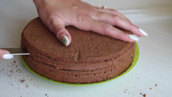 The Woman Cuts The Biscuit Cake. For Chocolate Cake With Peanuts