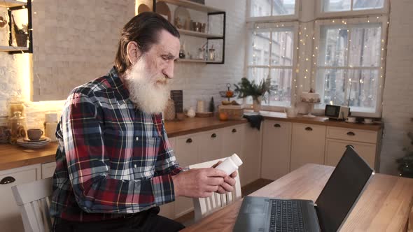 Elderly Man Communicates with Doctor Online Via Video Communication Using Laptop While Sitting at