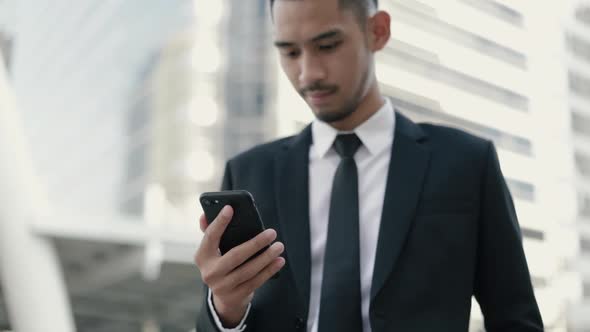 Attractive Asian businessman using a smartphone browsing social media.