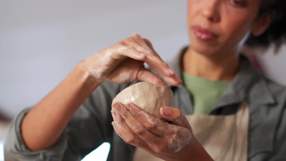 Woman smoothing the walls of the clay bowl