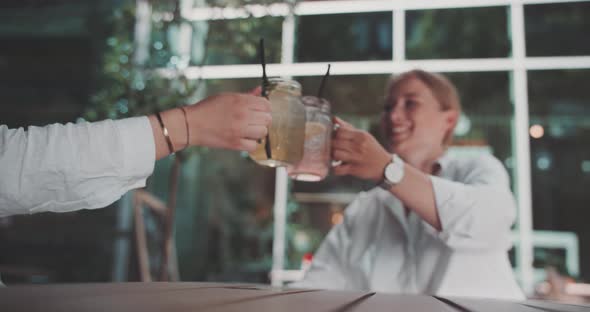 Two caucasian women cheering and drinking in a terrace