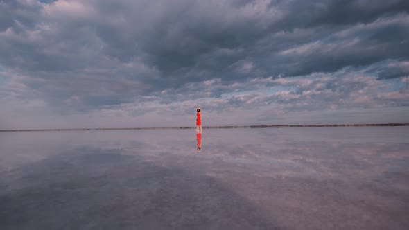 Tourist Girl Is Walking Along a Salt Lake in Which Clouds Are Reflected