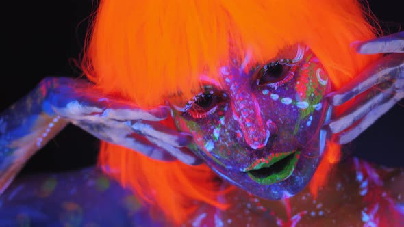 A Woman with a UV Pattern on Her Body and an Orange Wig Dancing in the Dark