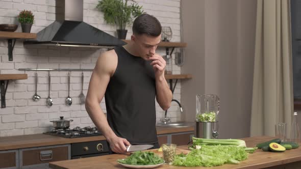 Athlete man preparing ingredients for smoothie in a modern kitchen. Preparation of vegetables