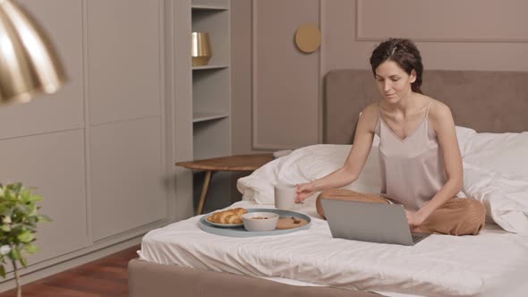 Woman Having Breakfast and Working in Bed