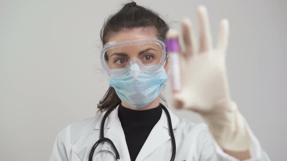 Doctor Holding Coronavirus Blood Test with Gloves, Protective Mask and Glasses