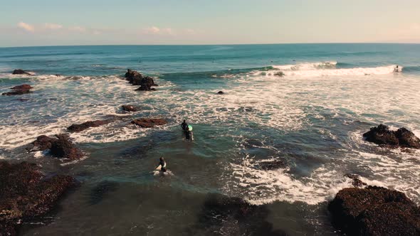 Three surfers entering the sea from the beach focusing on surfer girl at Punta de Lobos, Pichilemu-4