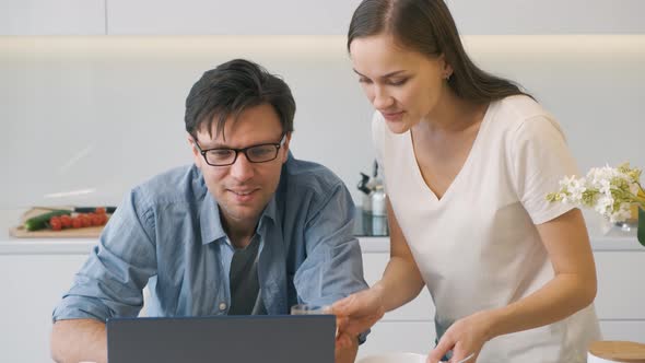 Cheerful Couple Looking at Screen of Laptop