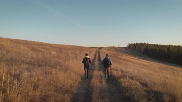 Happy Couple Man and Woman Tourist at Top of Mountain at Sunset Outdoors During a Hike. Silhouettes