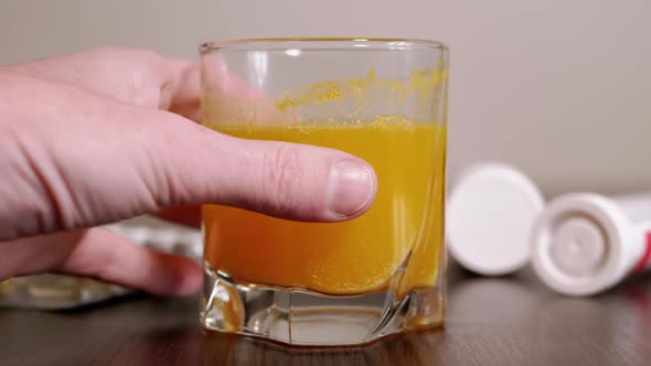 Female Reaches Out Hand to a Glass with of Dissolved Effervescent Tablet