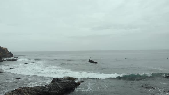 Aerial Dolly to the right along the waves on a cloudy day at Pichilemu, Chile-4K