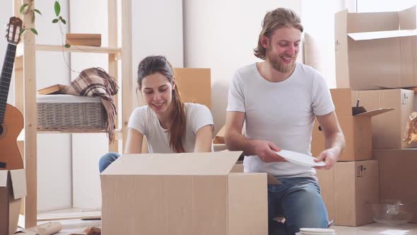 Cool Caucasian Pair Unpacking Dishes in Their New Flat in Slowmotion