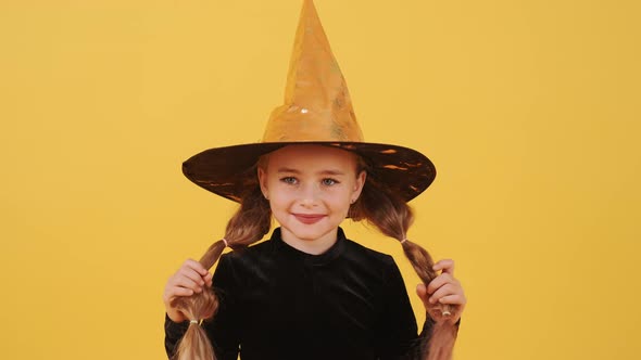 Little Blonde Girl in Witch Costume on Halloween at Orange Studio Background