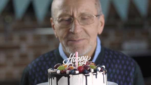  of Senior Man Blowing Candle on Cake